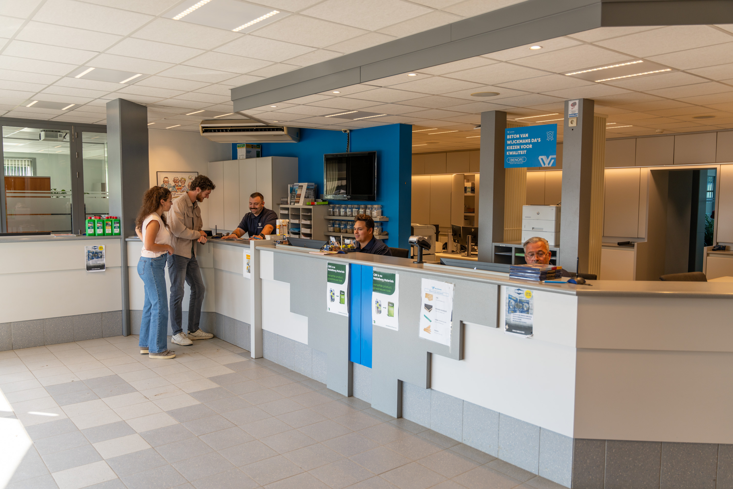 Een adviseur van Wijckmans spreekt met een koppel aan het onthaal van de bouwshop. 